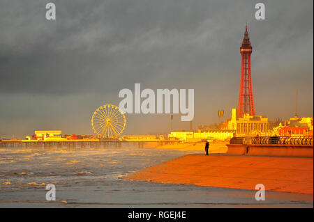 Blackpool,UK. 29th January 2019. A cold rainy day culminating in a dramatic sunset over an incoming tide. Central pier, the Ferris wheel and Blackpool Tower bathed in an orange glow at dusk. Kev Walsh/Alamy Live News Stock Photo