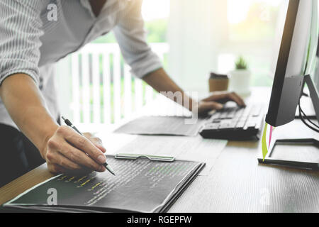 Serious busy hipster young web software developer programmer is coding or programming on a desktop computer information in modern office technologies  Stock Photo
