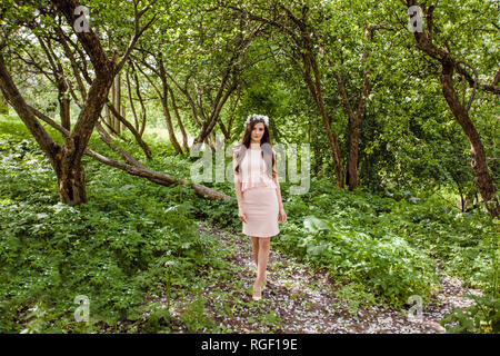 Pretty woman in pink dress walking in flowers garden outdoors Stock Photo