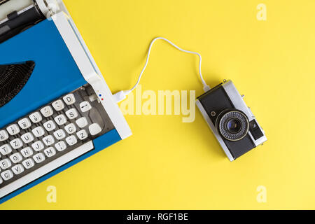 Flat lay of retro typewriter and photo camera connected with cable. Technology data transfer minimal creative concept. Stock Photo