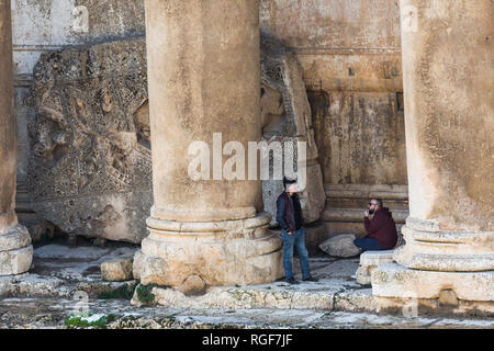 Two people having a chat at the columns' base of the Temple of Bacchus, Heliopolis Roman ruins, Baalbek, Lebanon Stock Photo