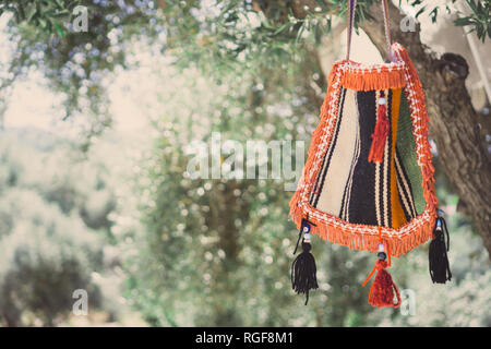 Authentic handmade colorful bag. Hanging on the tree for sale. Stock Photo