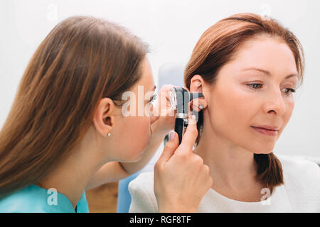 Mature woman getting ear exam at clinic Stock Photo