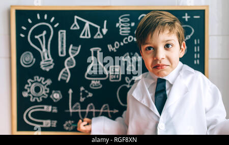 Child dressed as a scientist in front of chalkboard with drawings Stock Photo