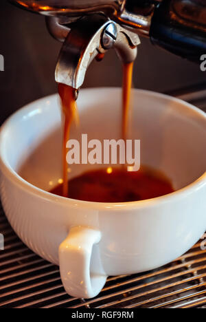 Close-up of a professional espresso machine pouring fresh coffee into a white ceramic cup Stock Photo