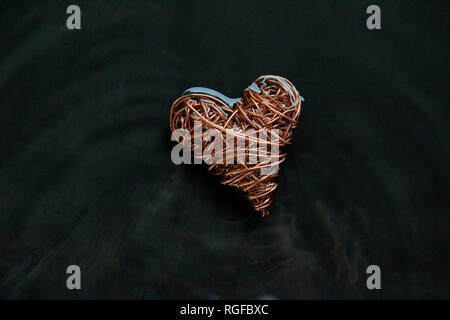 Copper wire heart made from reclaimed electric cable. Surrounding water  rocked to give lines of water movement