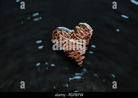Copper wire heart made from reclaimed electric cable. Highlights on concentric water ripples.