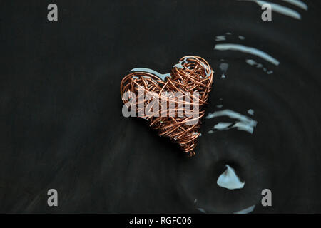 Copper wire heart made from reclaimed electric cable. Highlights on concentric water ripples