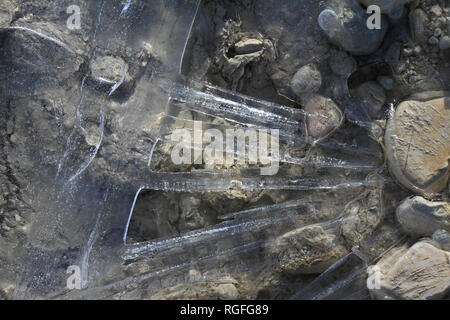 macro of an icy puddle or ice patterns on a gravel driveway in winter in Italy Stock Photo