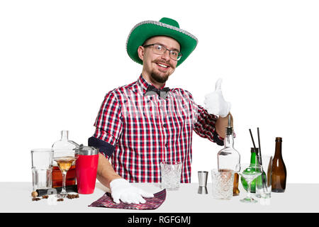 Expert male barman in hat is making cocktail at studio isolated on white background. International barman day, bar, alcohol, St. Patrick's Day celebration concept Stock Photo