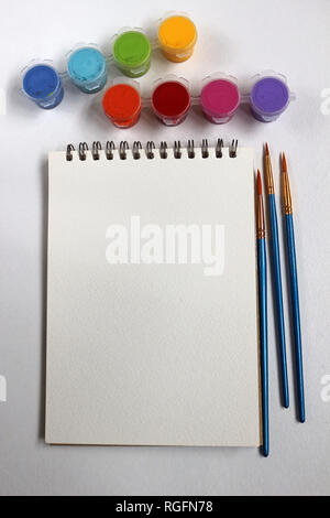 Blank Pad of Paper Surrounded by Paint Pots and Paint Brushes Stock Photo