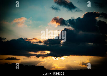 dark clouds against the evening sky and the rays of the setting sun Stock Photo