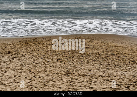 Gentle constructive waves rolling onto a sandy beach. Stock Photo