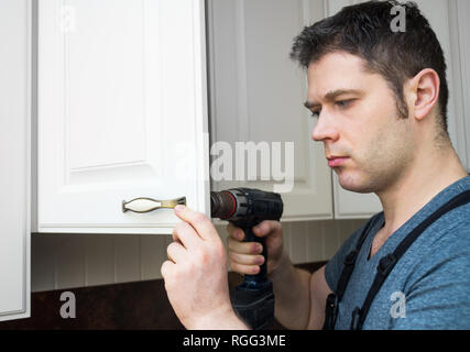 Professional handyman assembling kitchen door cabinet. Stock Photo