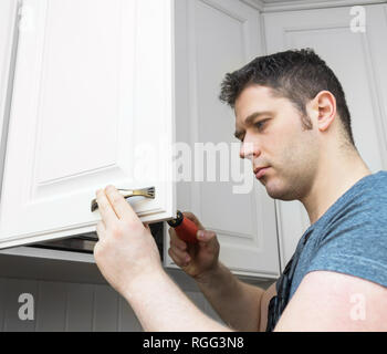 Professional handyman assembling kitchen door cabinet. Stock Photo