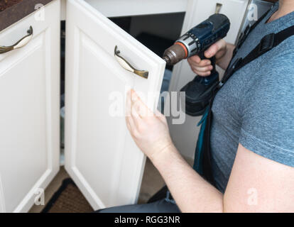 Professional handyman assembling kitchen door cabinet. Stock Photo