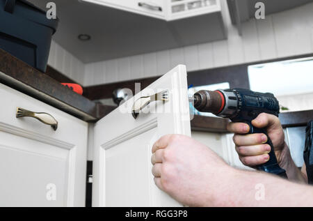 Professional handyman assembling kitchen door cabinet. Stock Photo