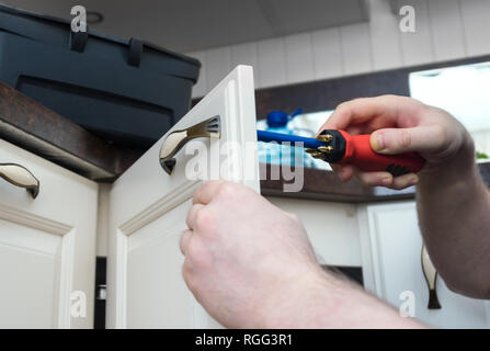 Professional handyman assembling kitchen door cabinet. Stock Photo