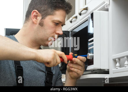 Male technician repairing microwave oven at home. Stock Photo