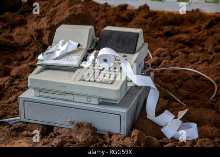 Old cash register with buttons and display. Cash register tape on old cash register. Cash register on brown ground background. Old cash register and c Stock Photo