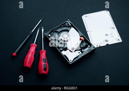 Data storage hard disk drive uncovered with assembly case cover part and screwdrivers, Computer hardware repair concepts. Stock Photo