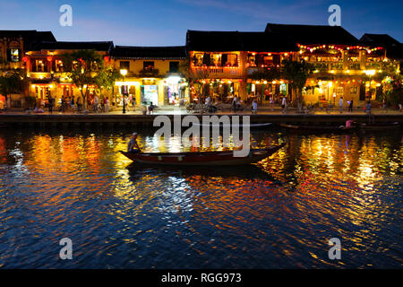 Boat sailing by illuminated houses reflected on the Thu Bon river in Hoi An, Vietnam Stock Photo