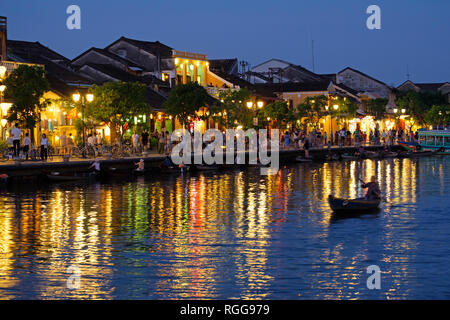 Boat sailing by illuminated houses reflected on the Thu Bon river in Hoi An, Vietnam Stock Photo