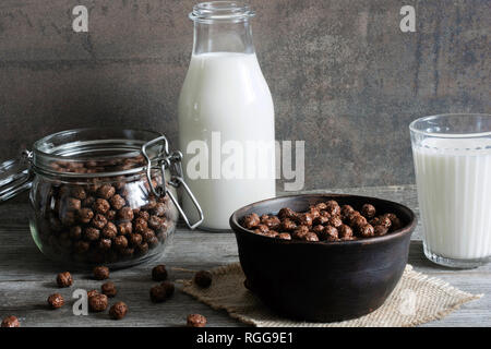 Sweet chocolate cereal balls for breakfast in a bowl with milk on rustic wooden background Stock Photo
