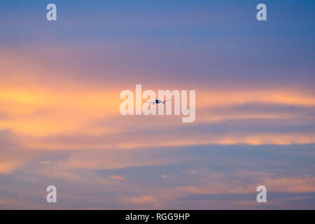 Silhouette of an airplane flying into the sunset Stock Photo