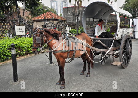 Manila, Philippines-October 24, 2016: Horse drawn kalesa-calash stops at Sta.Clara Street beside the Fort Santiago citadel while waiting for passenger Stock Photo