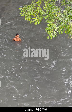 Manila, Philippines-October 24, 2016: Filipino boy takes a bath in the gray waters of the Pasig river as it comes under the Willian A.Jones Memorial B Stock Photo