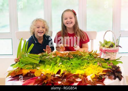 Kids pick colorful autumn leaves for school art project. Boy and girl making picture gluing fall leaf in rainbow color. Crafts for young children. Pre Stock Photo