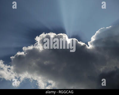 sun rays behind clouds in the sky Stock Photo