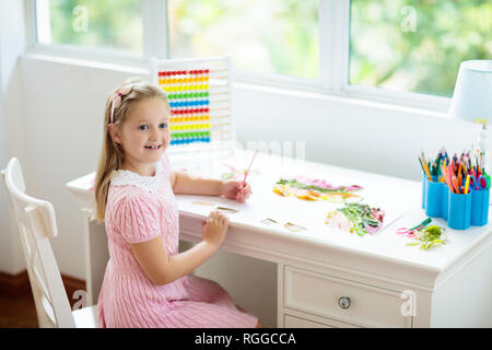 Child drawing rainbow. Kid painting at home. Little girl doing homework after school. Kids desk with abacus in white sunny bedroom. Children study, le Stock Photo