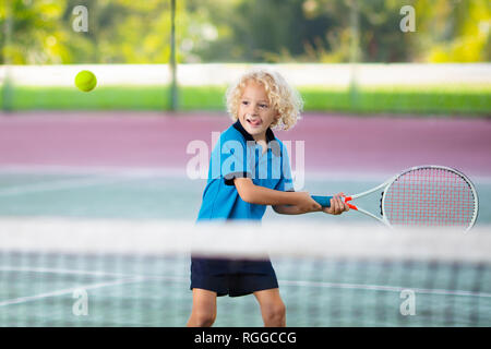 Child playing tennis on indoor court. Little boy with tennis racket and ball in sport club. Active exercise for kids. Summer activities for children.  Stock Photo