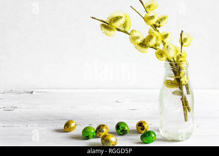 easter background with easter eggs and blooming willow branches in bottle on wooden table with copy space Stock Photo