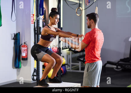 Trainer assisting client, doing box jumps Stock Photo