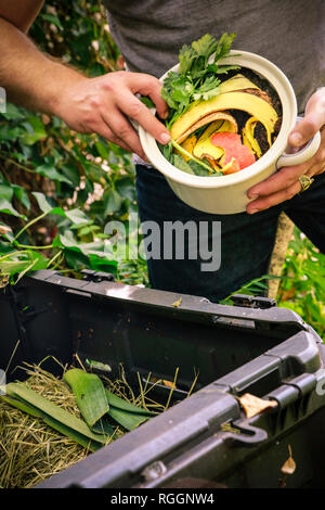 Mature man discarding kitchen scraps on compost pile Stock Photo