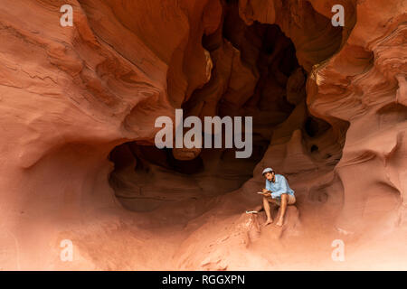 Young man sitting in a cave, taking notes Stock Photo