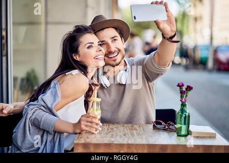 Happy young couple taking a selfie at outdoors cafe Stock Photo