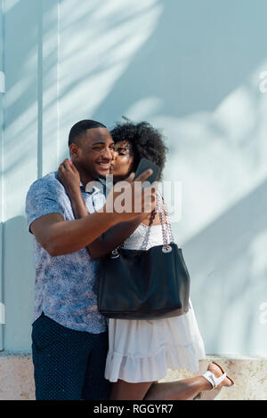 Smiling young couple embracing and taking a selfie Stock Photo