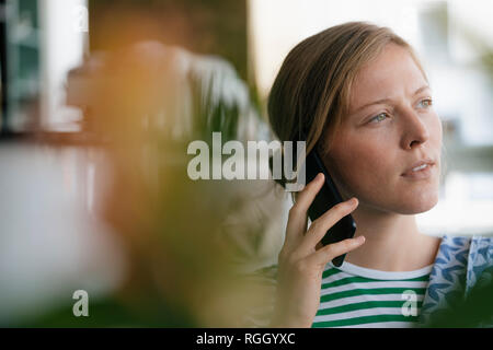 Portrait of young woman on cell phone in a cafe Stock Photo