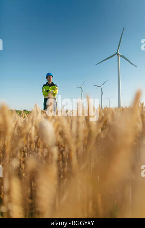 Engineer standing in a field at a wind farm Stock Photo