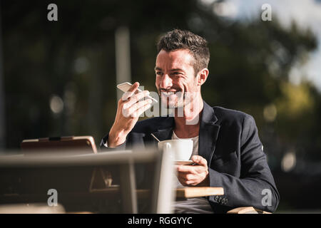 Businessman sitting in cafe, drinking coffee, using smartphone Stock Photo