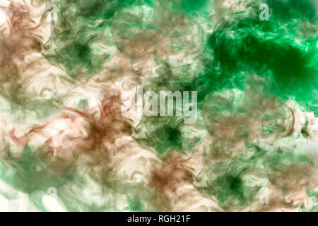 Beautiful pattern of smoke on a black background from the evaporating waves in the neon light of pink blue and purple as sea pebbles in the foam for T Stock Photo