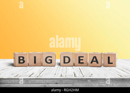 Big deal sign made of wooden cubes on a desk with a yellow wall in the background Stock Photo