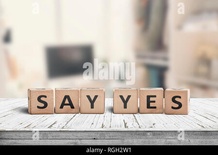 Say yes sign on a wooden desk in a bright room with a blurry background Stock Photo