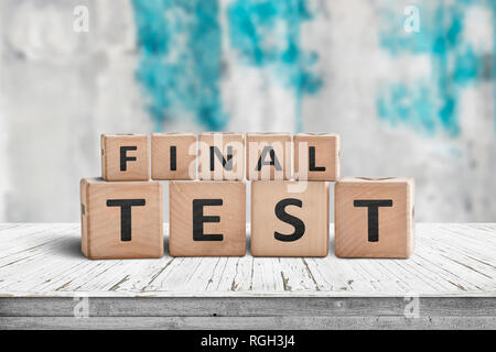 Final test spelled with letter cubes on a wooden table and a blurry blue background Stock Photo