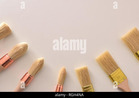 Set of paintbrushes for house painter of various sizes and shapes around on white table. Horizontal composition
