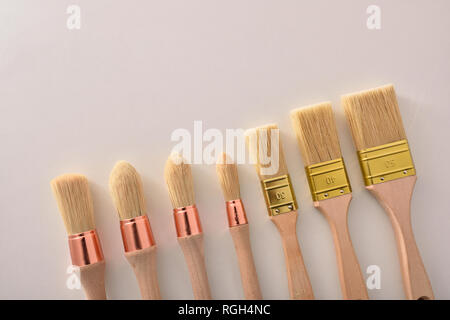 Set of paintbrushes for house painter of various sizes and shapes aligned diagonal on white table. Horizontal composition